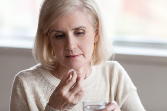 older-woman-holding-pill-and-glass-of-water